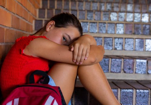 portrait-sad-caucasian-schoolgirl-with-school-bag-sitting-stairs-school (1)